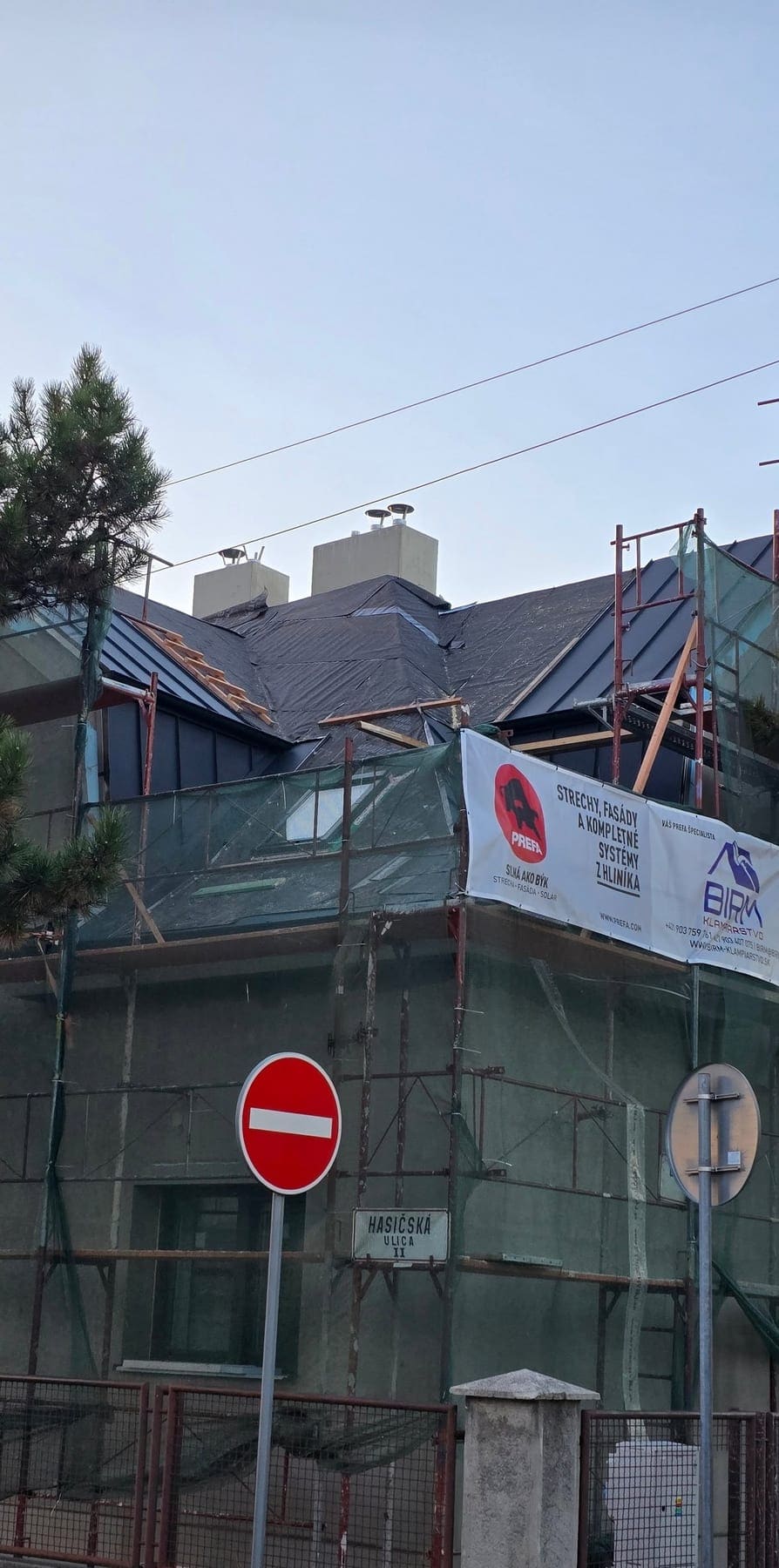 Rekonštrukcia strechy rodinného domu v lešení s bannerom Prefa a BIRM-Klampiarstvo, Bratislava