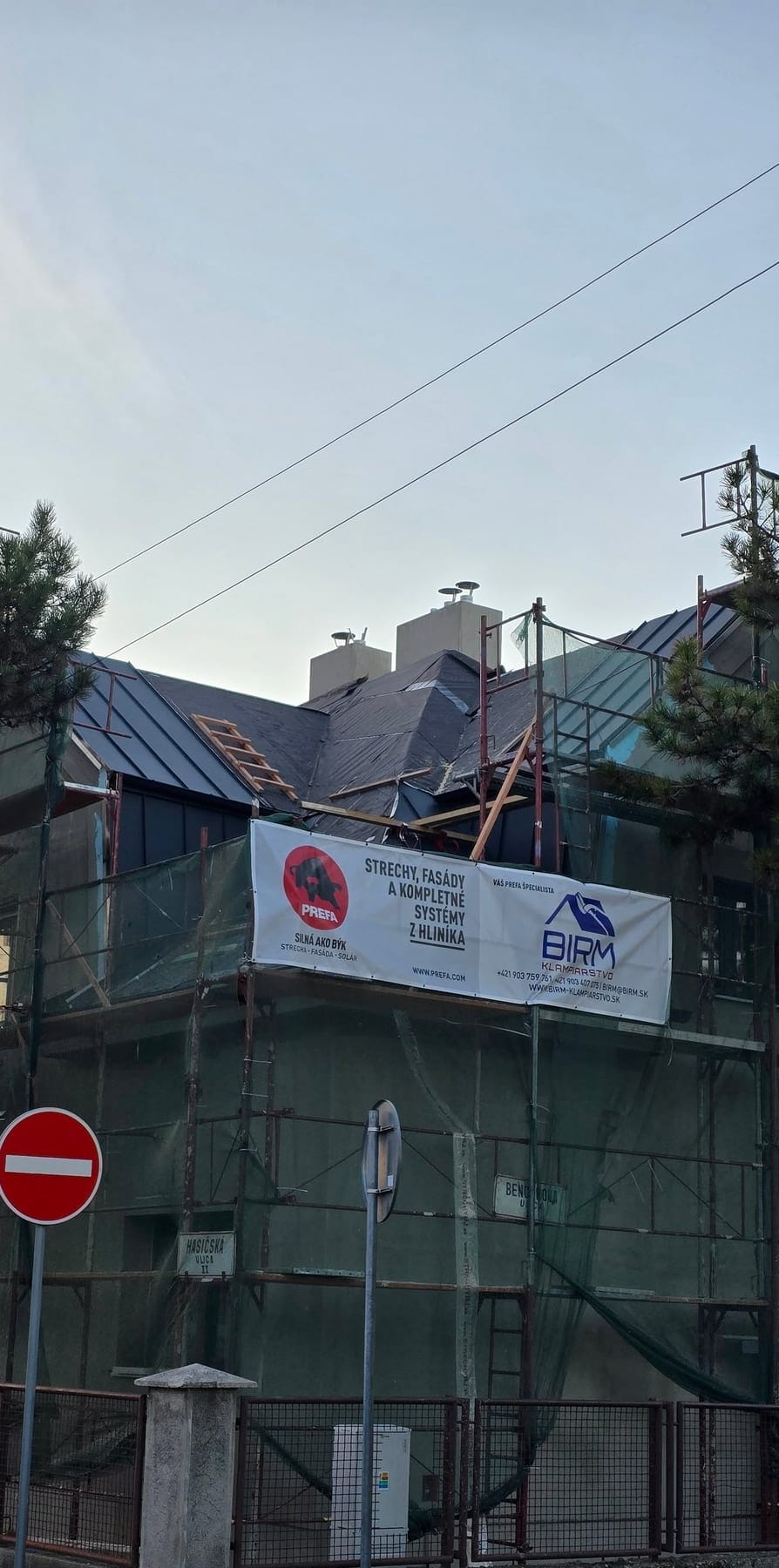 Rekonštrukcia strechy v lešení s bannerom Prefa a BIRM-Klampiarstvo
