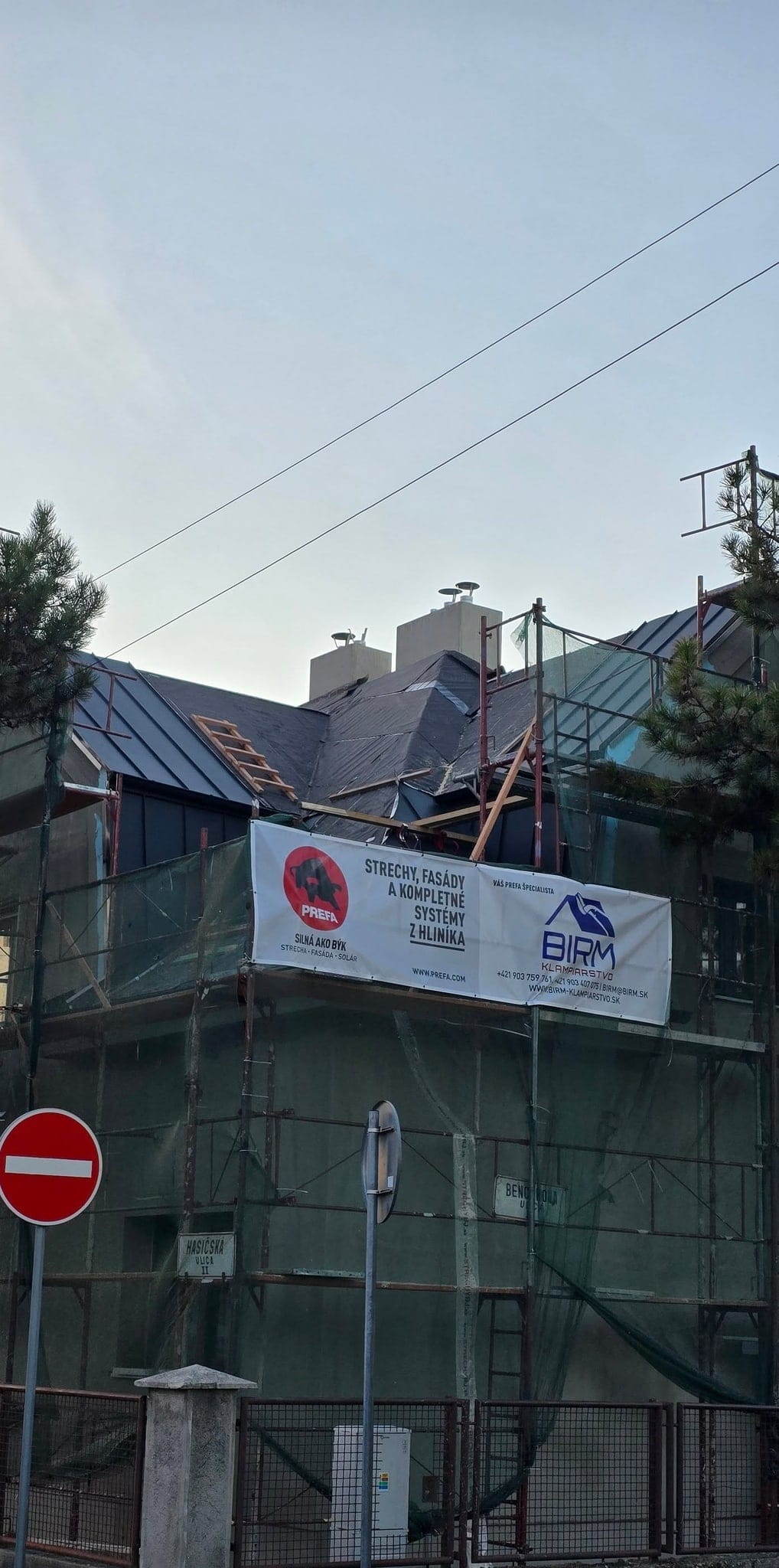 Rodinný dom v lešení počas rekonštrukcie strechy s bannerom BIRM-Klampiarstvo, Bratislava